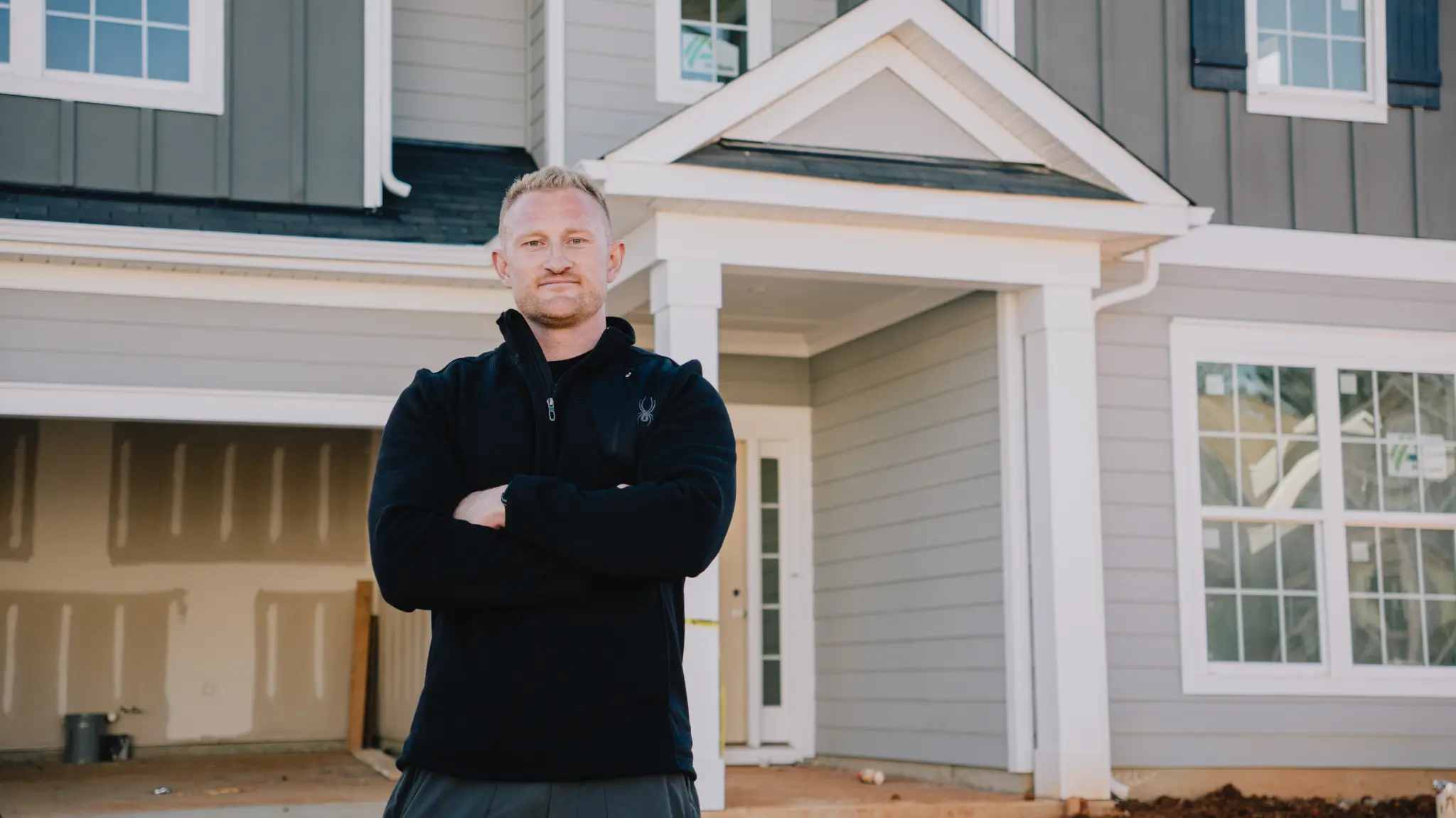 Essential Insights on Home Inspections in Charlotte, NC A man stands with his arms crossed in front of a house under construction.
